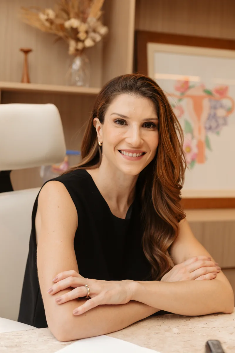 Dra. Camila Cinquetti sorrindo à mesa do consultório